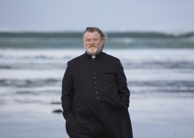 Father James (Brandon Gleeson) walks along an Irish beach were a parishioner plans to kill him for sins of a long-dead priest in 