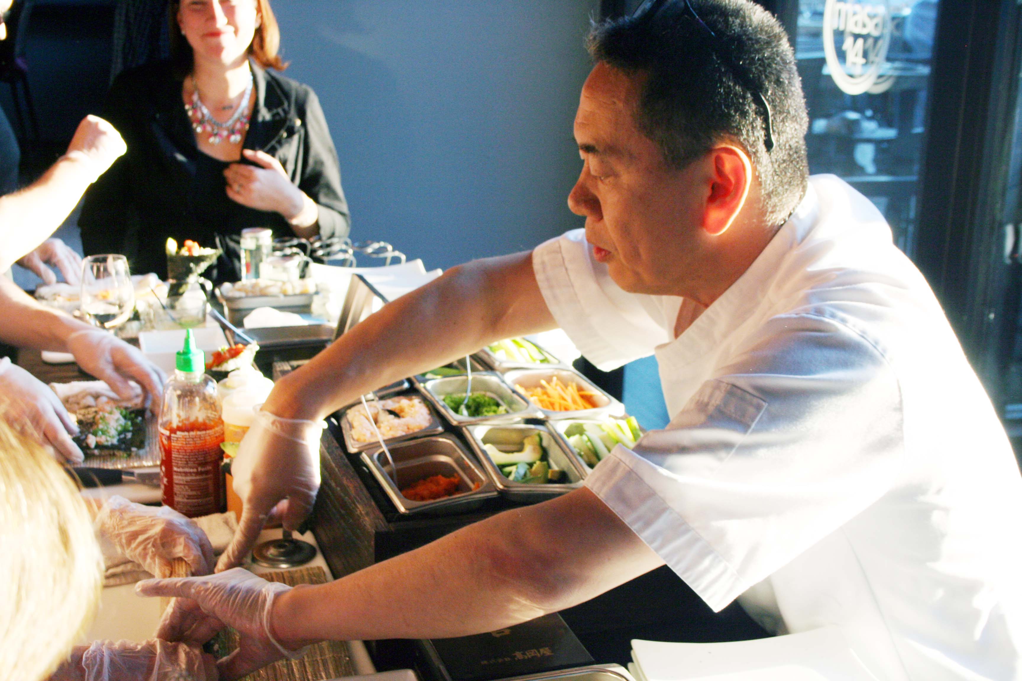 Sushi chef Kaz Okochi helps a student roll her inside-out roll. (Photo: Mark Heckathorn/DC on Heels)