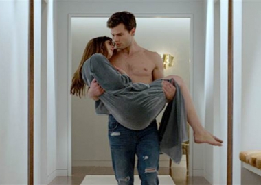 Christian Grey (Jamie Dornan) carries Anastasia Steele (Dakota Johnson) in Fifty Shades of Grey.