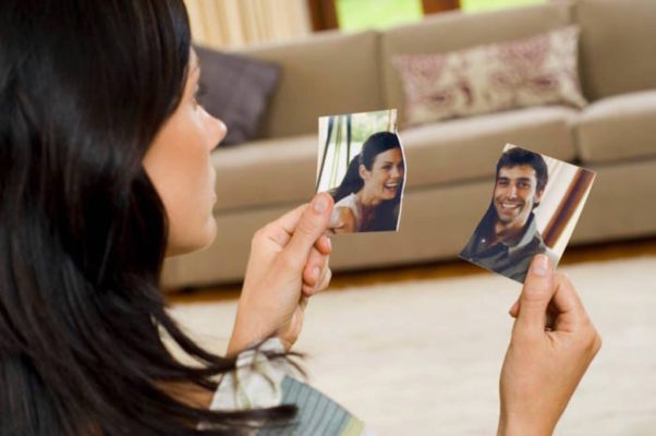 Woman holding a ripped photo of her and a man. (Photo: datetricks.com)
