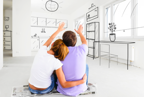 A comples sitting on a box looking at a drawing of what they want their new house to look like. (Photo: Dreamstime)