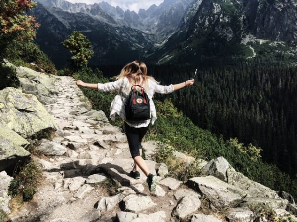 woman hiking on mountain side with backpack (Photo: Nina Uhikova/Pexels)