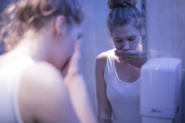 woman in bathroom mirror wiping her mouth (Photo: KatarzynaBialasiewicz/Getty Images)