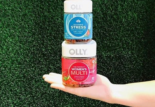 Hand holding a bottle of Olly Goodbye Stress supplemets atop a bottle of Women's Multi vitamins. (Photo: Olly Nutrition/Instagram)