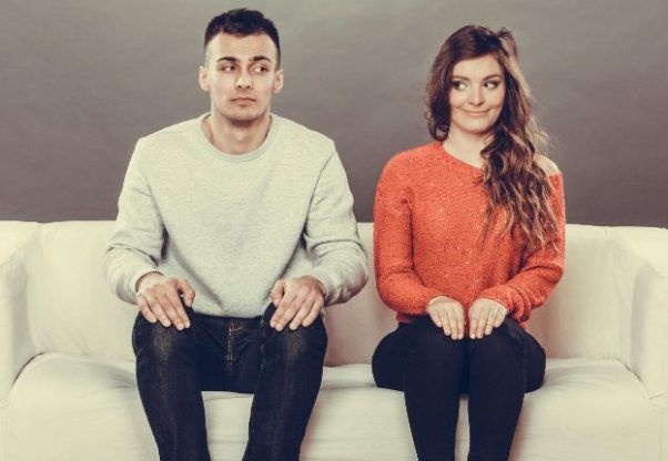 Man and woman awkwardly sitting on a couch. (Photo: Shutterstock)