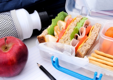 A lunchbox with a sandwich, fresh carrots, crackers, an apple and a bottle of water. (Photo: Shuttertsotck)