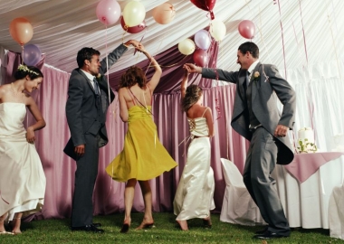 Two couples dancing at a wedding, with a single woman off to the left dancing by herself. (Photo: Getty Images)