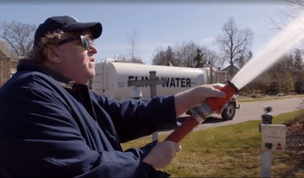 Michael Moore sprays water from a firehose connected to a tanker truck with Flint, Michigan painted on it, onto the lawn of Michigan's governor. (Photo: Briarcliff Entertainment)