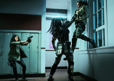 The Predator holding a man up in the air by his throat while Olivia Munn points a gun at the alien. (Photo: 20th Century Fox)
