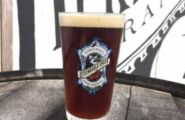 a glass of Lickinghole Creek beer sitting on top of a barrel. (Photo: Lickinghole Creek Craft Brewery)