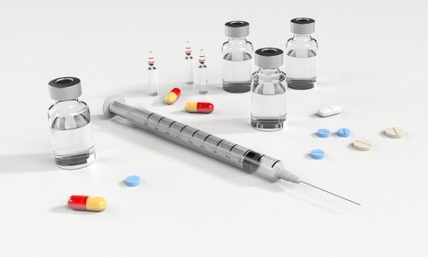 pills, a syringe and vials scattered on a white counter. (Photo: quimono/Pixabay)
