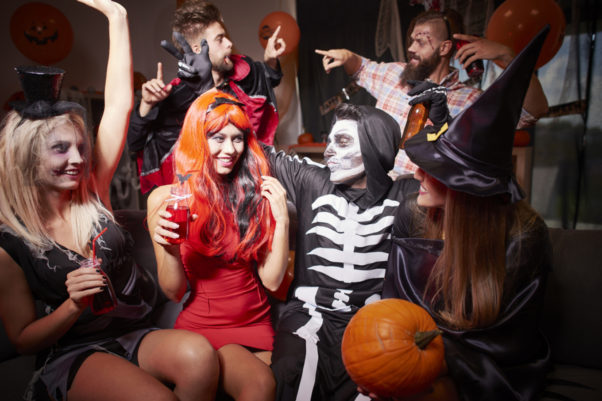 Three men and three women dressed in Halloween Costumes including witch, skelton and vampire at a house party. (Photo: Shutterstock)