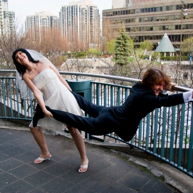 A bridge pulling a groom by his ankles while he hold onto a railing. (Photo: Alex Indigo/Flickr)