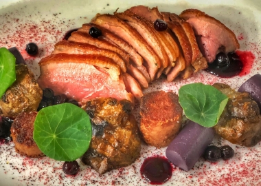 Sliced duck breast and leg confit on a plate with sunchoke, cassis, blueberry and hibiscus. (Photo: Jordan Hammes)