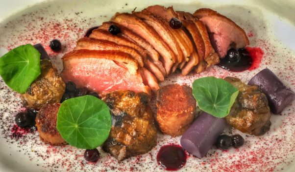 Sliced duck breast and leg confit on a plate with sunchoke, cassis, blueberry and hibiscus. (Photo: Jordan Hammes)