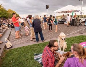 Visitors sit on the boardwalk and in the grass at Yards Park listening to a band under a canopy. (Photo: Capitol Riverfront)