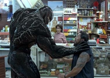 Venom grabs a male Asian robber by the shoulder as the female Asian clerk looks on horrified. (Photo: Sony Pictures)