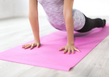 A woman on a pink yoga mat pushing her shoulders up with her arm with her legs on the ground. (Photo: Burst/Pexels)