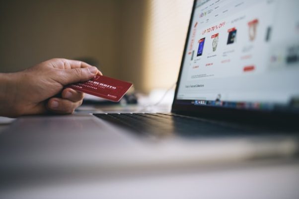 a hand holding a credit card beside a laptop on an ebay page. (Photo: Negative Space/Pexels)