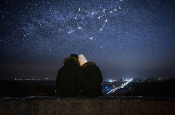 A man and woman sitting outside under stars forming a heart with an arrow through it. (Photo: 123RF.com)