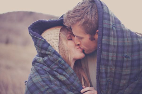 man and woman outside snuggling under and blue and green plaid blanket. (Photo: weheartit.com)