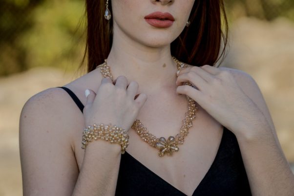 woman in a black dress wearing gold earing, necklace and bracelet. (Photo: Media/Pexels)