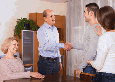 A boyfriend shaking the hand of his girlfriend's father as girlfriend and mother look on. (Photo: Shutterstock)