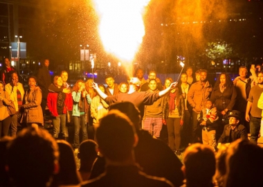 A man breathes a ball of fire into the air at Yards Park while surrounded by spectators. (Photo: Yards Park)
