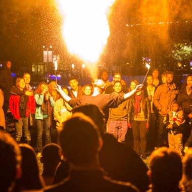 A man breathes a ball of fire into the air at Yards Park while surrounded by spectators. (Photo: Yards Park)