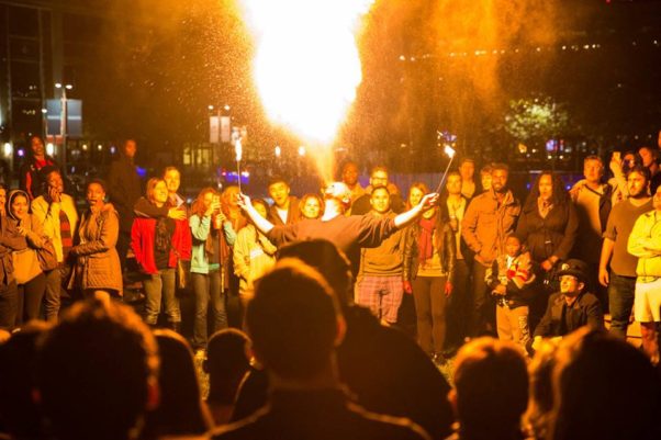 A man breathes a ball of fire into the air at Yards Park while surrounded by spectators. (Photo: Yards Park)