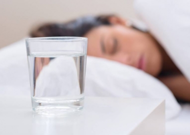 A woman sleeping in bed with a glass of water on the nightstand. (Photo: Shutterstock)
