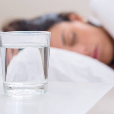A woman sleeping in bed with a glass of water on the nightstand. (Photo: Shutterstock)