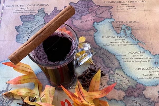 Vin brulee in a clear mug with a cinnamon stick sitting on top. The mug is on a map of Italy with fall leaves around it. (Photo: Lupo Verde Osteria)