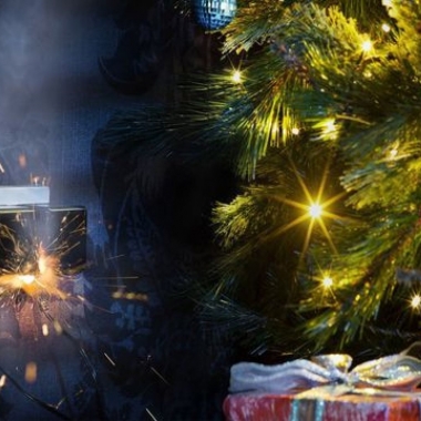 Christmas tree with gifts underneath beside an outlet with 2 things plugged in that are sparking. (Photo: iStock)