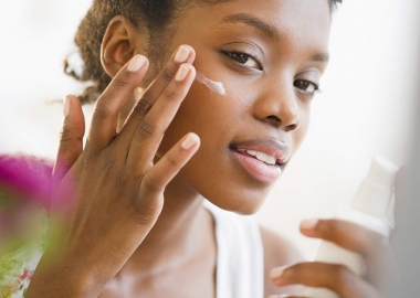 A black woman putting sunblock on her face. (Photo: Getty Images)