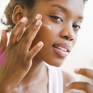A black woman putting sunblock on her face. (Photo: Getty Images)