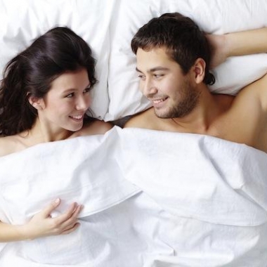 Man and woman in bed under the sheets staring at each other. (Photo: Shutterstock)