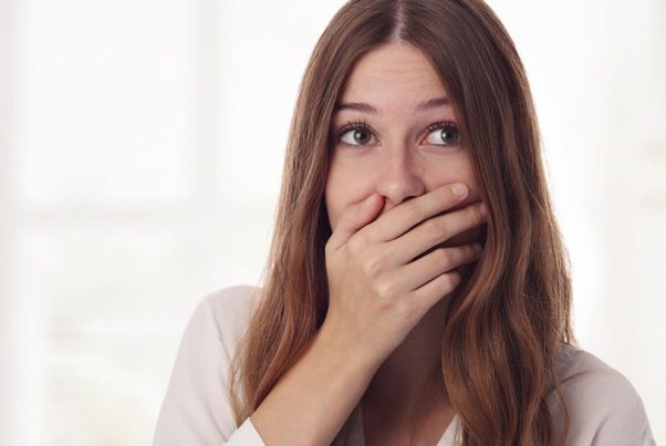 Woman with hiccups covering her mouth with her hand. (Photo: Getty Images)