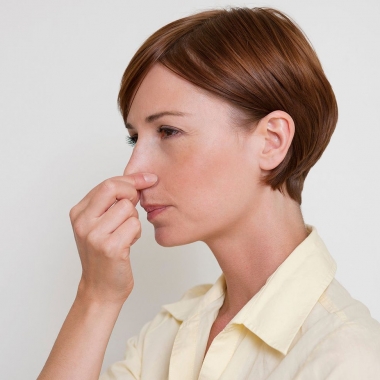 A woman pinching her nose while holding her breath. (Photo: Masterfile)