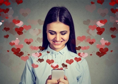Happy woman sending love texts with red and pink hearts coming out of her cell phone. (Photo: Shutterstock)