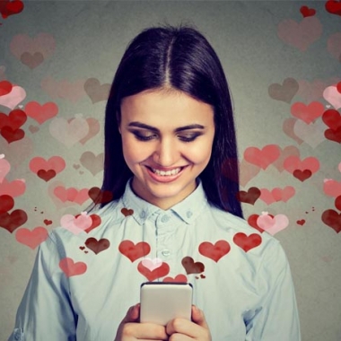 Happy woman sending love texts with red and pink hearts coming out of her cell phone. (Photo: Shutterstock)