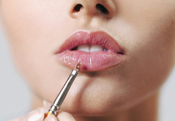 Woman applying lip paint to her full lips. (Photo: Getty Images)