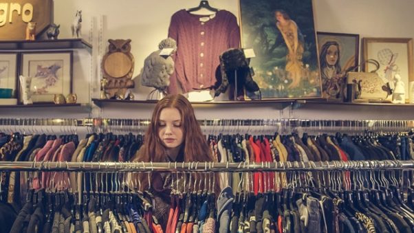 A woman looking through clothes on a rack. (Photo: Burst/Pexels)