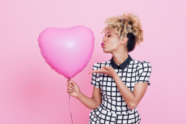 Young woman with big pink heart balloon. (Photo: Getty Images)