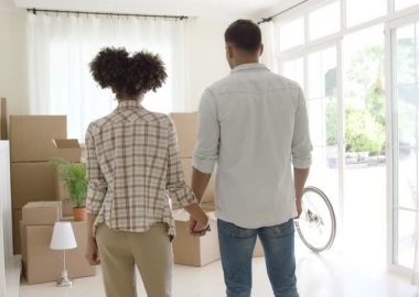 An African American couple holding hands looking at a pile of moving boxes. (Photo: Shutterstock)