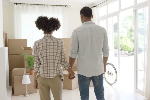 An African American couple holding hands looking at a pile of moving boxes. (Photo: Shutterstock)