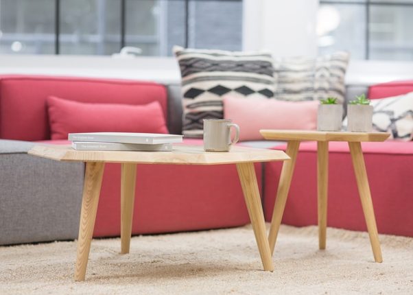 A wood coffee table infrontof a pink sofa with a book and coffee mug on it. (Photo: StockSnap/Pixabay)