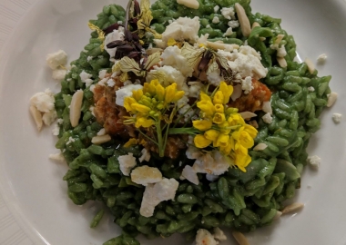 Dish & Dram's nettle risotto in a white bowl topped with toasted almond slivers and local edible baby yellow flowers. (Photo: The Dish & Dram)