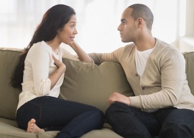 A Hispanic couple having a confersation sitting on a couch. (Photo: Getty Images)