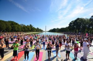 A crowd of people doing yoga around the reflecting pool in front of the Lincoln Memorial. (Photo: Yoga on the Mall)